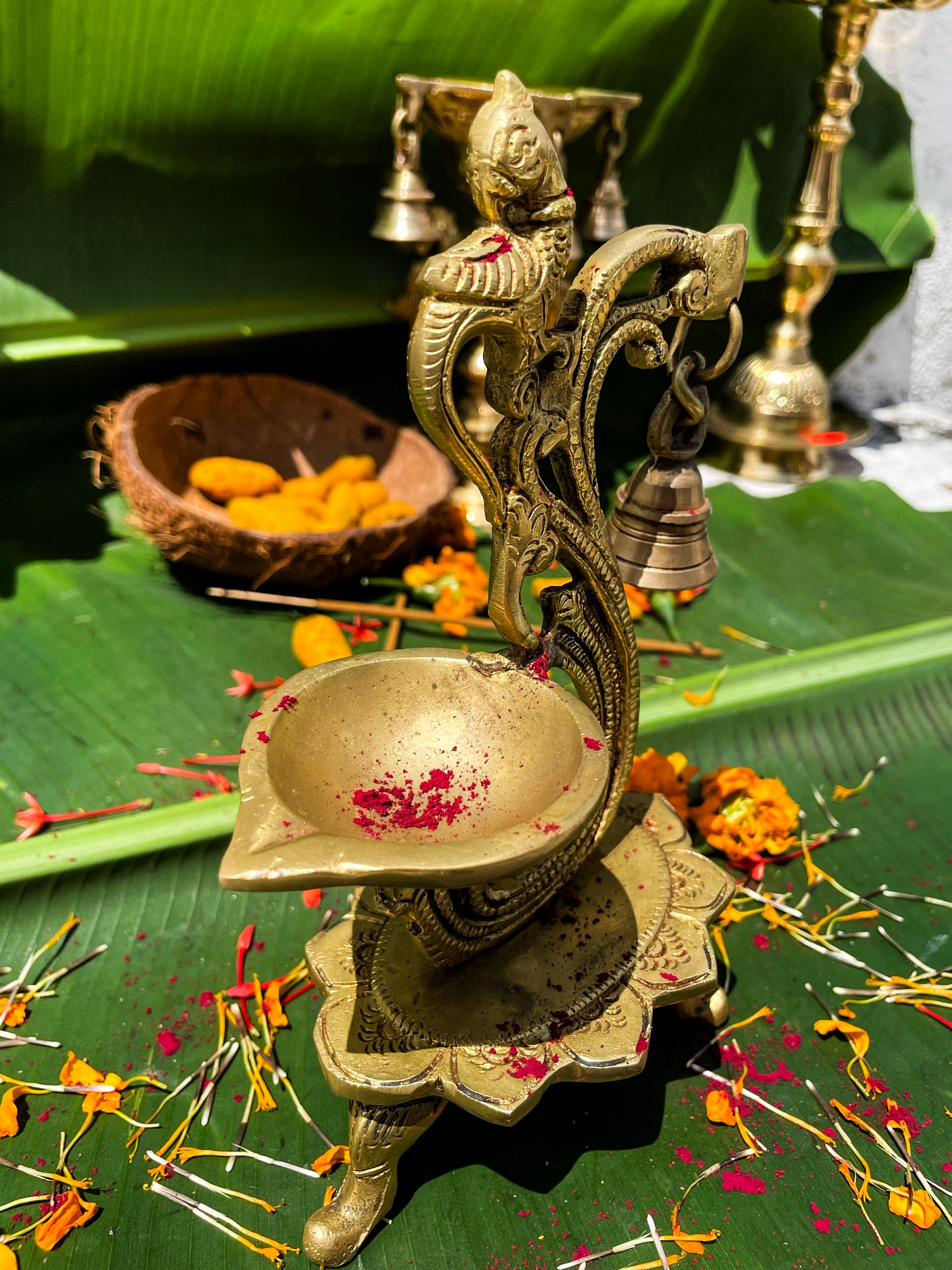 Decorative brass lamp on a green leaf with flowers and small bells in the background